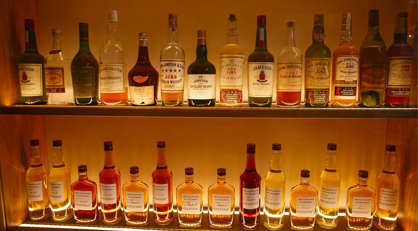 Vintage John Jameson & Son Dublin whiskey bottles backlit on a distillery shelf
