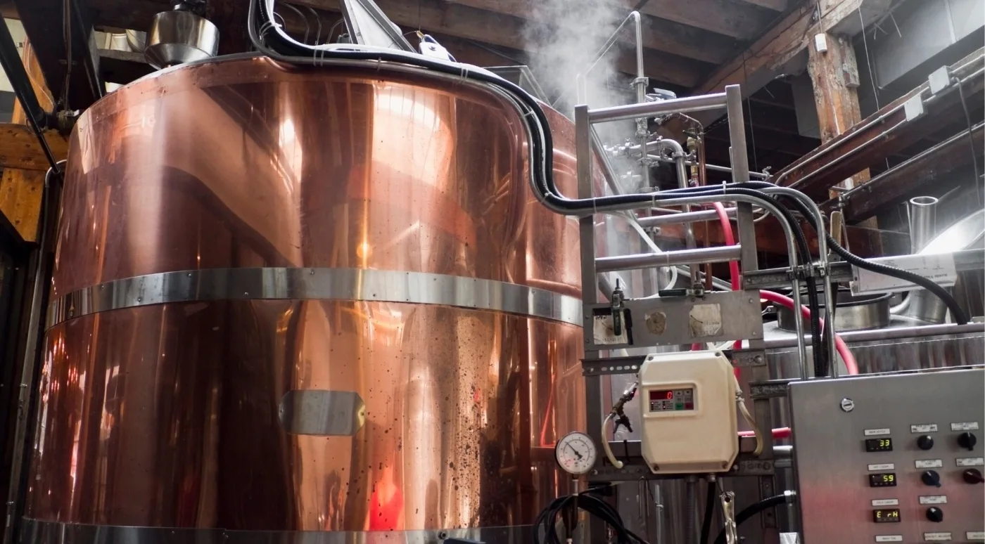 A working copper still with steam and gauges at a Dublin craft distillery
